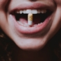 Woman holding pill between teeth
