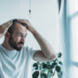 Man inspecting hair loss in mirror